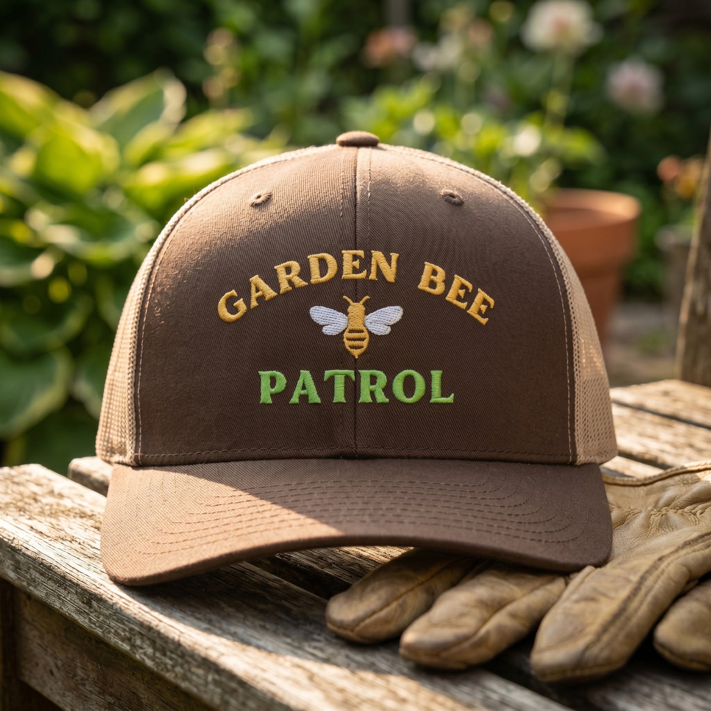 Brown cap with 'Garden Bee Patrol' text and a bee logo on a wooden surface with gloves.